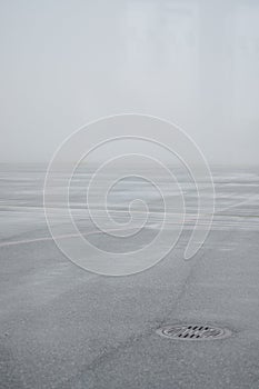 Foggy overlay on the airport runway. Bad weather overcast. Iron sewer hatch and asphalt on runway are very icy