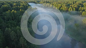A foggy river flowing through a forested landscape viewed from above