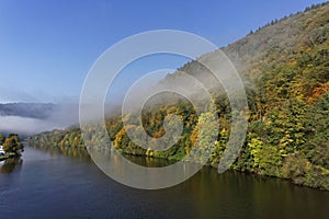 Foggy river landscape and forest in autumn colors