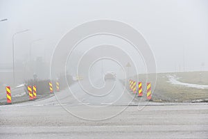 foggy road with roadwork signs and car photo