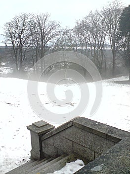 Foggy, snowy day scene with steps leading down to grass area photo