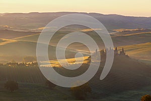 Foggy sunrise over the rural house with vineyards in San Quirico d'Orcia