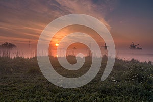 Foggy sunrise with the siloute of the windmills