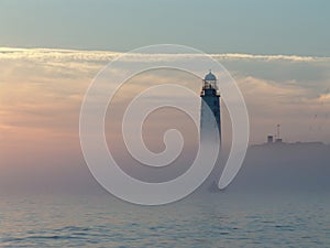 Foggy sunset,small boat and lighthouse