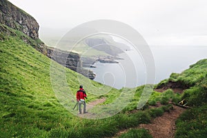 Foggy view of Mykines island with tourist in red jacket