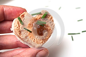foie gras on bread in shaped heart in hand on white background