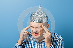 Foil hat on man. Man closed his eyes. Protects from reading think