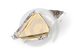 Foil wrapped processed creame cheese slice isolated on a white background. Small triangular piece of portioned soft cheese in a