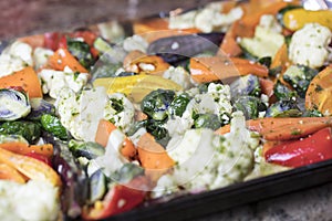 Foiled lined baking sheet filled with raw carrots, cauliflower,