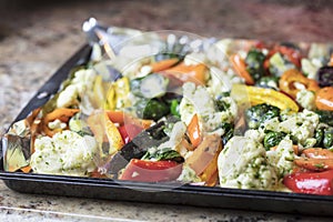 Foiled lined baking sheet filled with raw carrots, cauliflower,