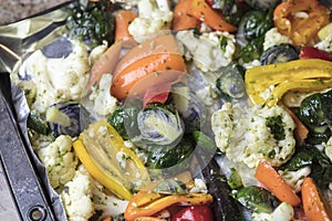 Foiled lined baking sheet filled with raw carrots, cauliflower,