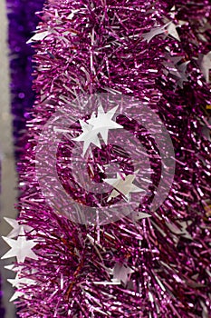 Foiled shiny lilac purple tinsel with white stars, close-up background backdrop. Vertical stripes shiny garland christmas