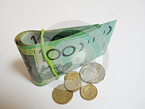 Fold of green Australian $100 dollar notes plus coin