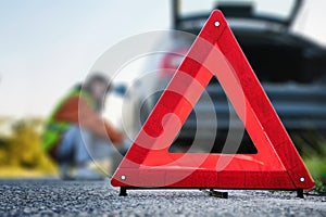 Fold-out warning road sign, driver changes wheel in the background