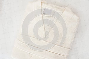 Folded bathrobe on bed in room. White robe