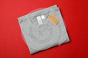 Folded blank grey t-shirt with tag on red background