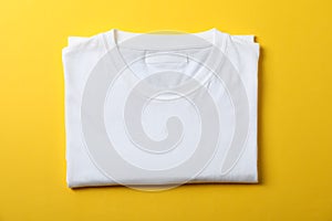 Folded blank white t-shirt on yellow background