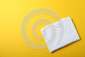 Folded blank white t-shirt on yellow background