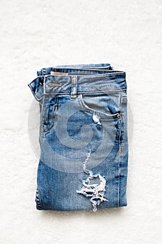 Folded blue jeans lie on a white background
