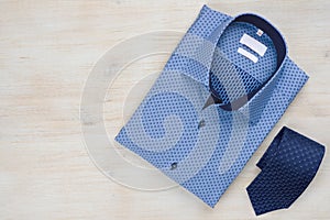 Folded blue man shirt and tie on wooden background