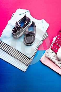 Folded blue and pink bodysuit with boat shoes on it on minimalistic pink and blue background. diaper for newborn boy and girl. Sta