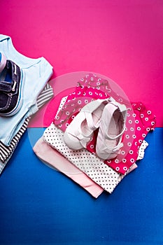 Folded blue and pink bodysuit with boat shoes on it on minimalistic pink and blue background. diaper for newborn boy and girl. Sta