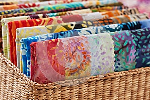 Folded bright pieces of quilting batik fabrics in a basket, macro