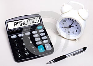 Folded business papers, pen, glasses, a flower in a pot and a tablet with a sheet of paper with the text ANALITICS on the desktop