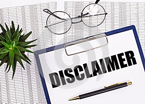 Folded business papers, pen, glasses, a flower in a pot and a tablet with a sheet of paper with the text DISCLAIMER on the desktop