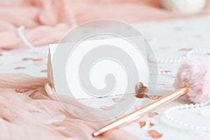 Folded card near pink decorations, hearts and tulle on white table close up, mockup