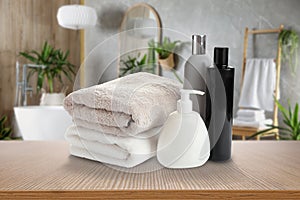 Folded clean towels and toiletries on wooden table in bathroom