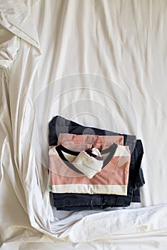 Folded clothes on an unmade bed