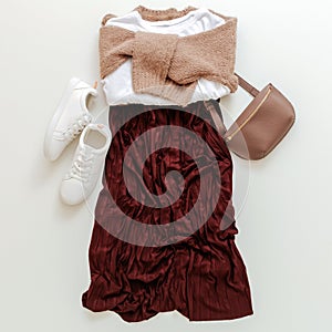 Folded clothes for women fashion urban basic outfit. Female spring look autumn outfit burgundy skirt beige sweater white shoes