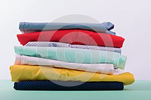 Folded colorful pants and jeans. Stack of bright female trousers. Close up.