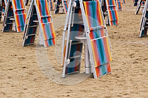 Folded deck chairs at sandy beach at seaside