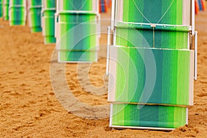 Folded deck chairs at sandy beach at seaside