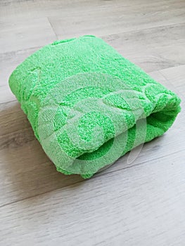 folded green towel on wooden background