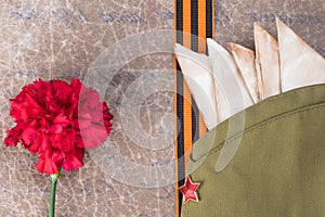 Folded letters in a military cap with a star, a St. George ribbon and a red flower on the background of an old letter