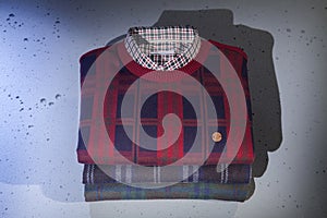 Folded men`s sweaters and shirts. checked sweaters isolated