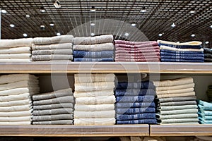 Folded multicolored towels on shelves. Neatly folded clothes. Rack of clothes with warm. Cotton towels neatly folded