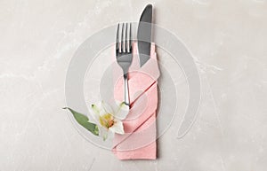 Folded napkin with fork, knife and flower on table