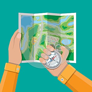 Folded paper city map and compass in hands