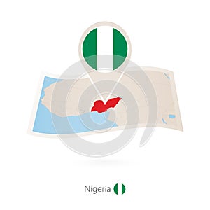 Folded paper map of Nigeria with flag pin of Nigeria