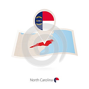 Folded paper map of North Carolina U.S. State with flag pin of North Carolina