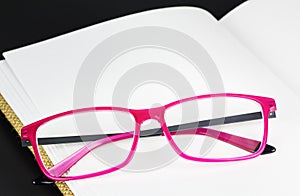 Folded pink glasses on book