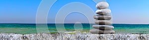 Folded pyramid of smooth stones on the seashore. Pebble on beach