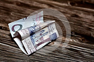 Folded Saudi Arabia money of 5 SAR five riyals isolated on wooden background, wrinkled 5 Saudi Riyals cash bill banknote