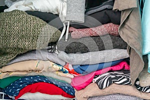 Folded sweaters and garments of a woman`s wardrobe in a closet. Depicting excess, the need for closet organization, tidyin photo