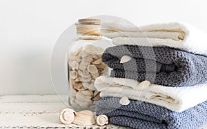 Folded towels near a bottle with seashells on a white wooden table. Spa and wellness, cotton terry textile. Ecological theme