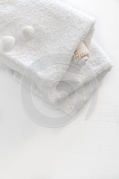 Folded two white towels on a white wooden table. Spa and wellness, cotton terry textile. Ecological theme